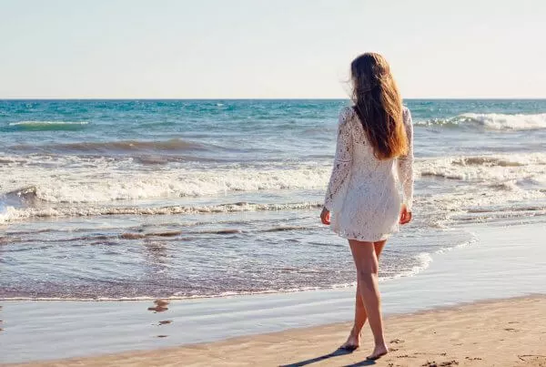 woman on beach wearing white dress with long brunette hair